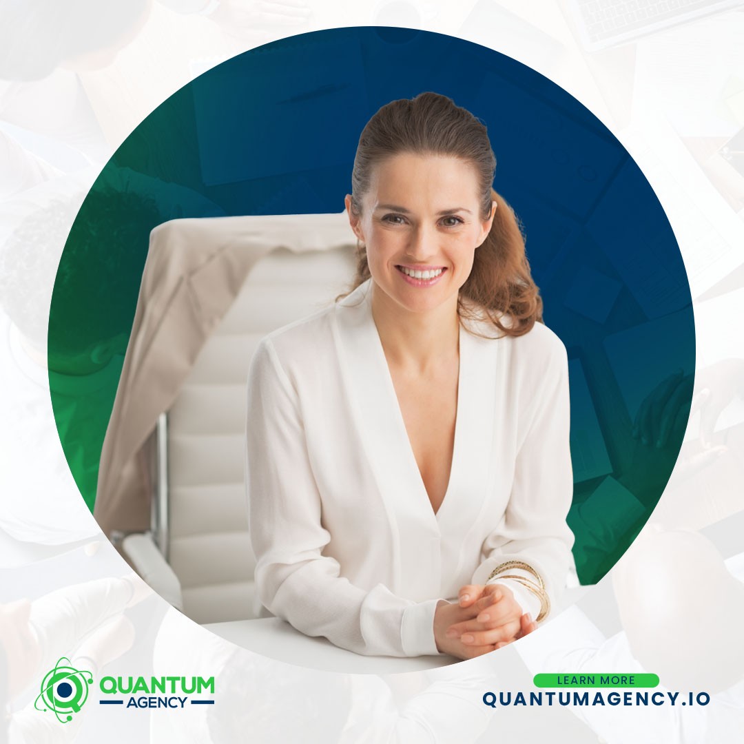 Corporate branding graphic from Quantum Agency showing a smiling female executive in a white blouse sitting at a desk with her hands clasped. The central image is framed in a large circle with the Quantum Agency logo and a "Learn More quantumagency.io" call to action in the bottom corner.