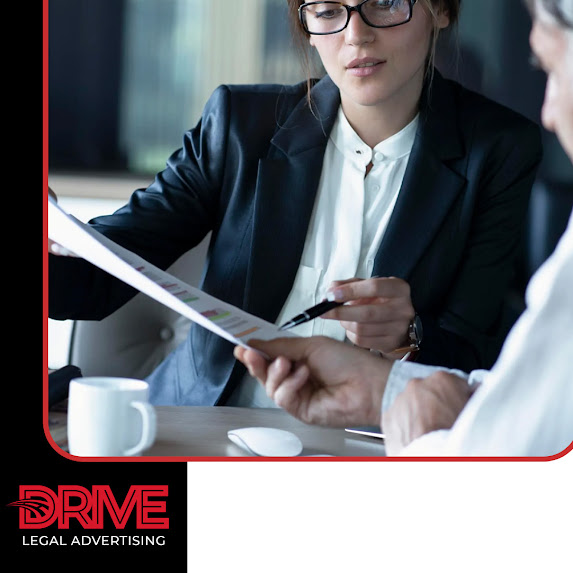 Female attorney or legal consultant wearing glasses reviewing marketing charts and document strategy with a client, branded for Drive Legal Advertising LLC.
